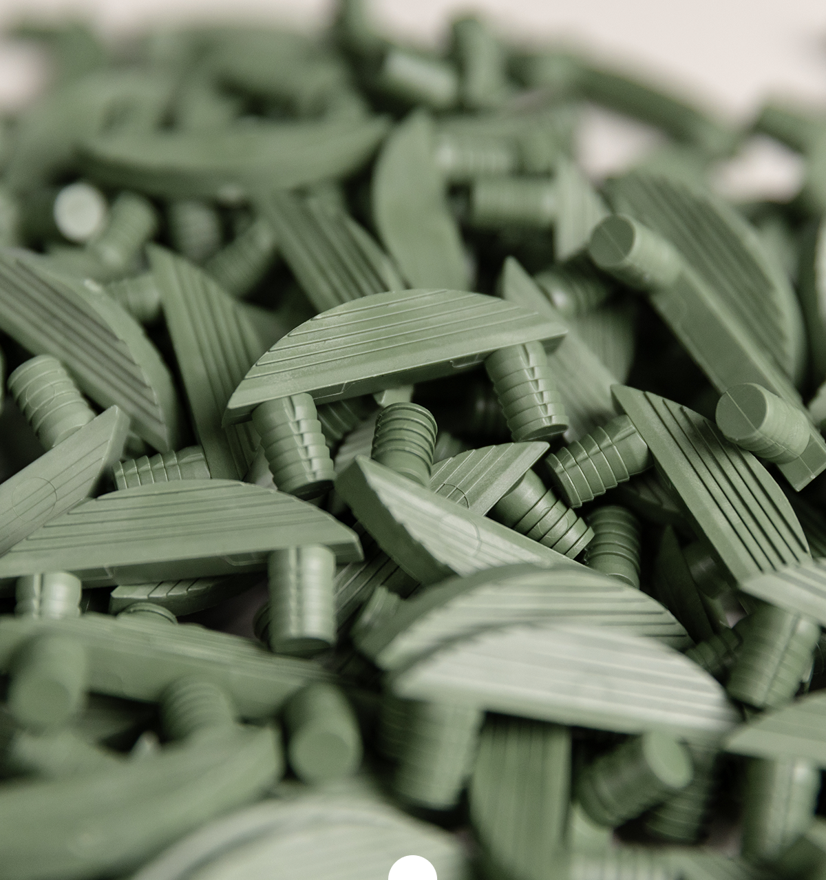 Mehrere grüne Möbelverbinder mit Steckdübeln in Nahaufnahme, lose gestapelt als Serienprodukt
